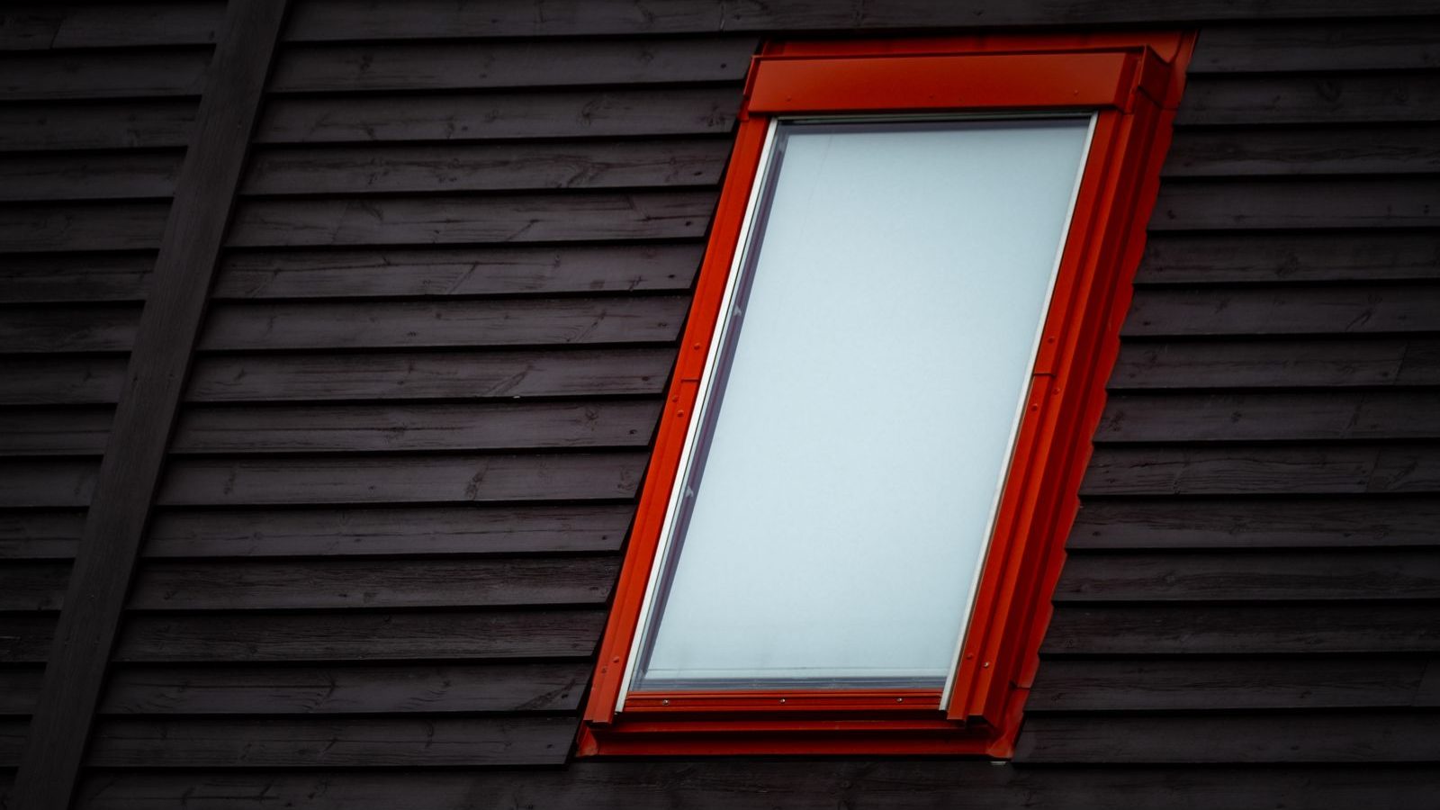 Dachfenster mit rotem Rahmen in dunkler Holzverkleidung