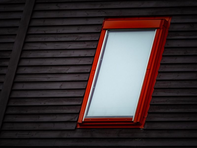 Dachfenster mit rotem Rahmen in dunkler Holzverkleidung
